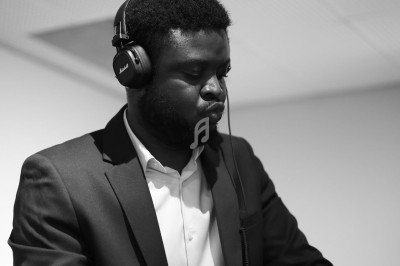 Un homme en costume joue de la musique avec un casque audio dans un environnement intérieur.
