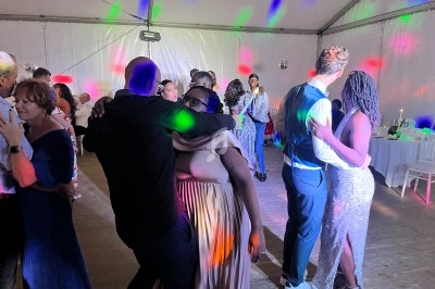 Personnes dansant sous des lumières colorées dans une salle éclairée, ambiance festive et conviviale.