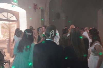 Groupe de personnes dans une salle de réception dansante, éclairée par des lumières vertes et une ambiance tamisée.