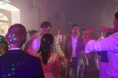 Personnes dansant sous des lumières colorées dans une salle enfumée lors d'une fête ou d'un événement.