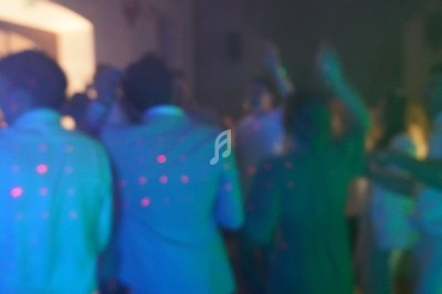 Personnes dansant dans une ambiance tamisée avec des lumières colorées et des points lumineux projetés.