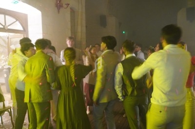Groupe de personnes dansant dans une salle faiblement éclairée avec des lumières colorées.