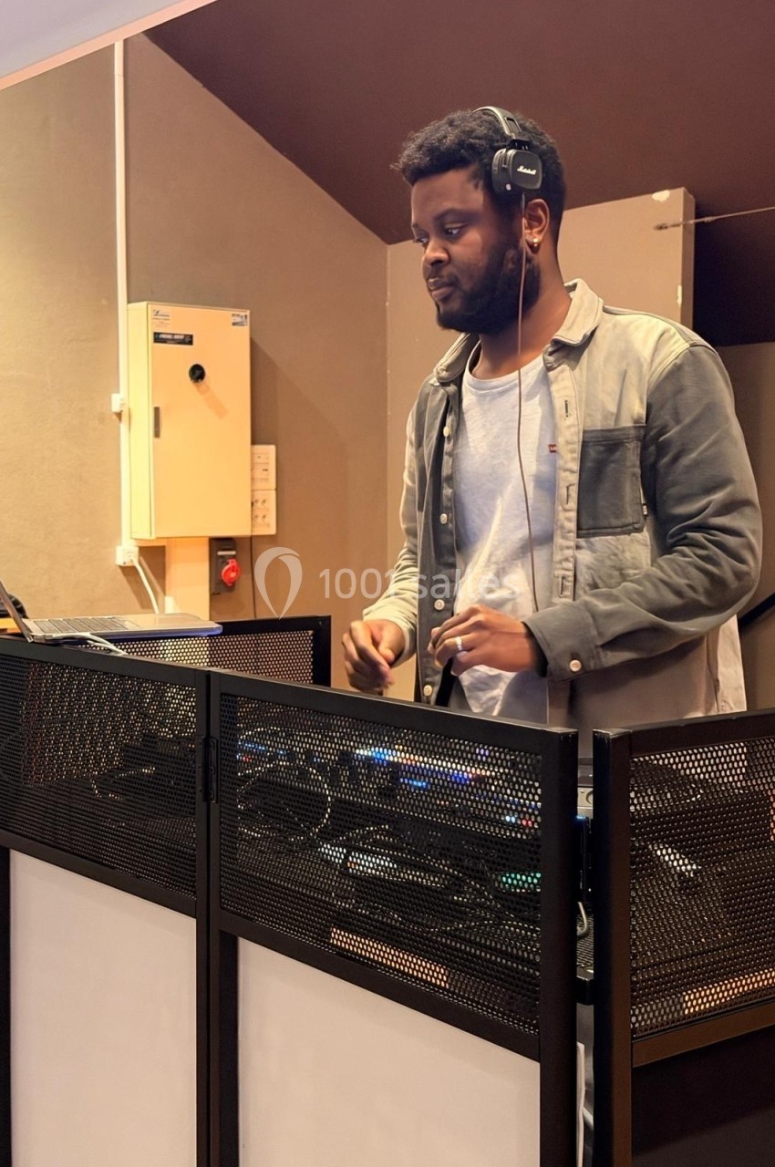 Un DJ mixant de la musique sur une console dans une salle intérieure.