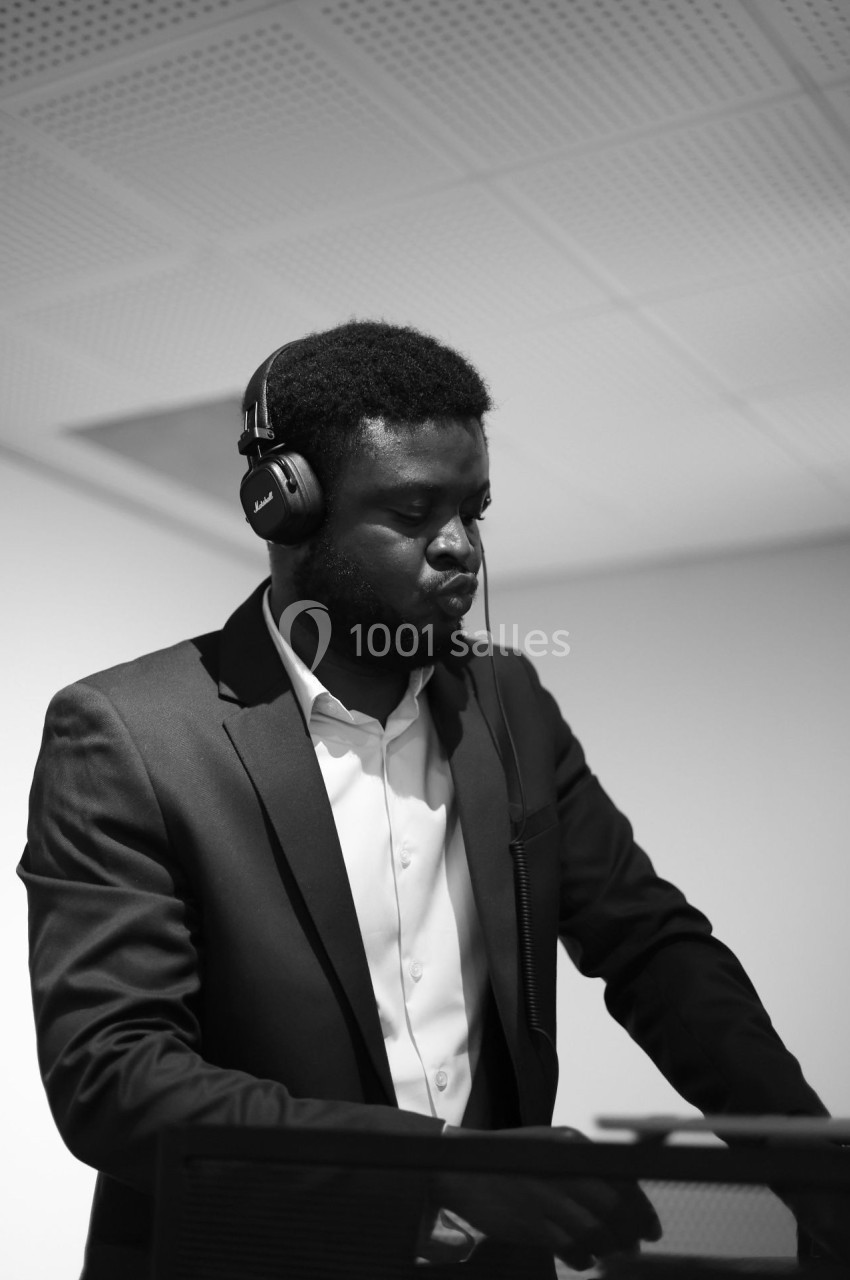 Un homme en costume joue de la musique avec un casque audio dans un environnement intérieur.