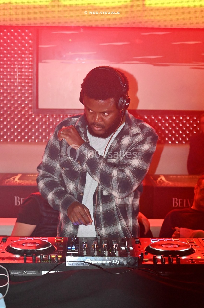 Un DJ mixant de la musique sur des platines dans une ambiance lumineuse rouge.