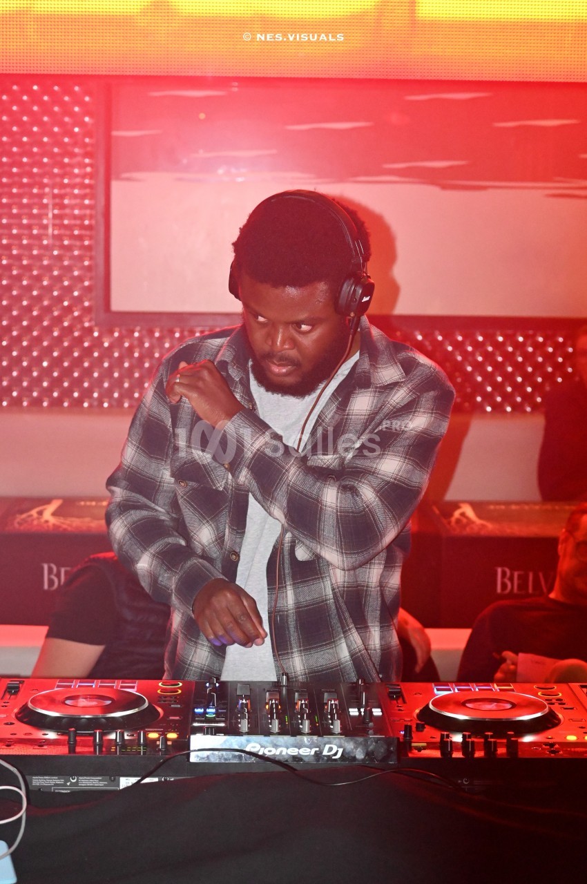 Un DJ mixant de la musique sur des platines dans une ambiance lumineuse rouge.