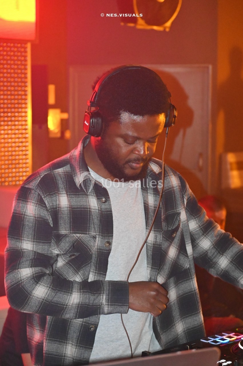 Un homme portant un casque audio mixe de la musique sur une table de mixage dans un environnement éclairé.