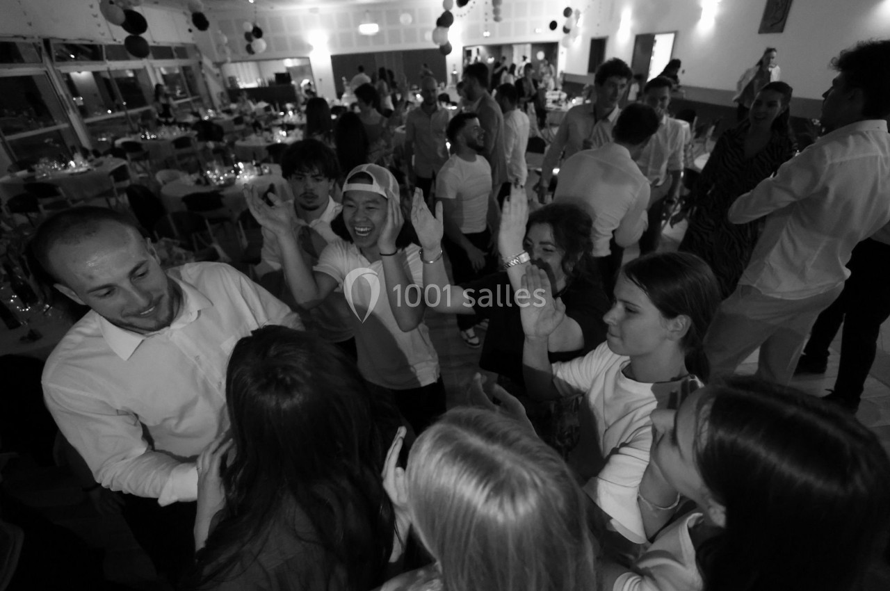 Groupe de personnes discutant et s'amusant dans une salle de réception animée en noir et blanc.