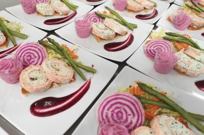 Assiettes dressées avec des roulés de volaille, légumes râpés et décorations de sauce, en préparation en cuisine.