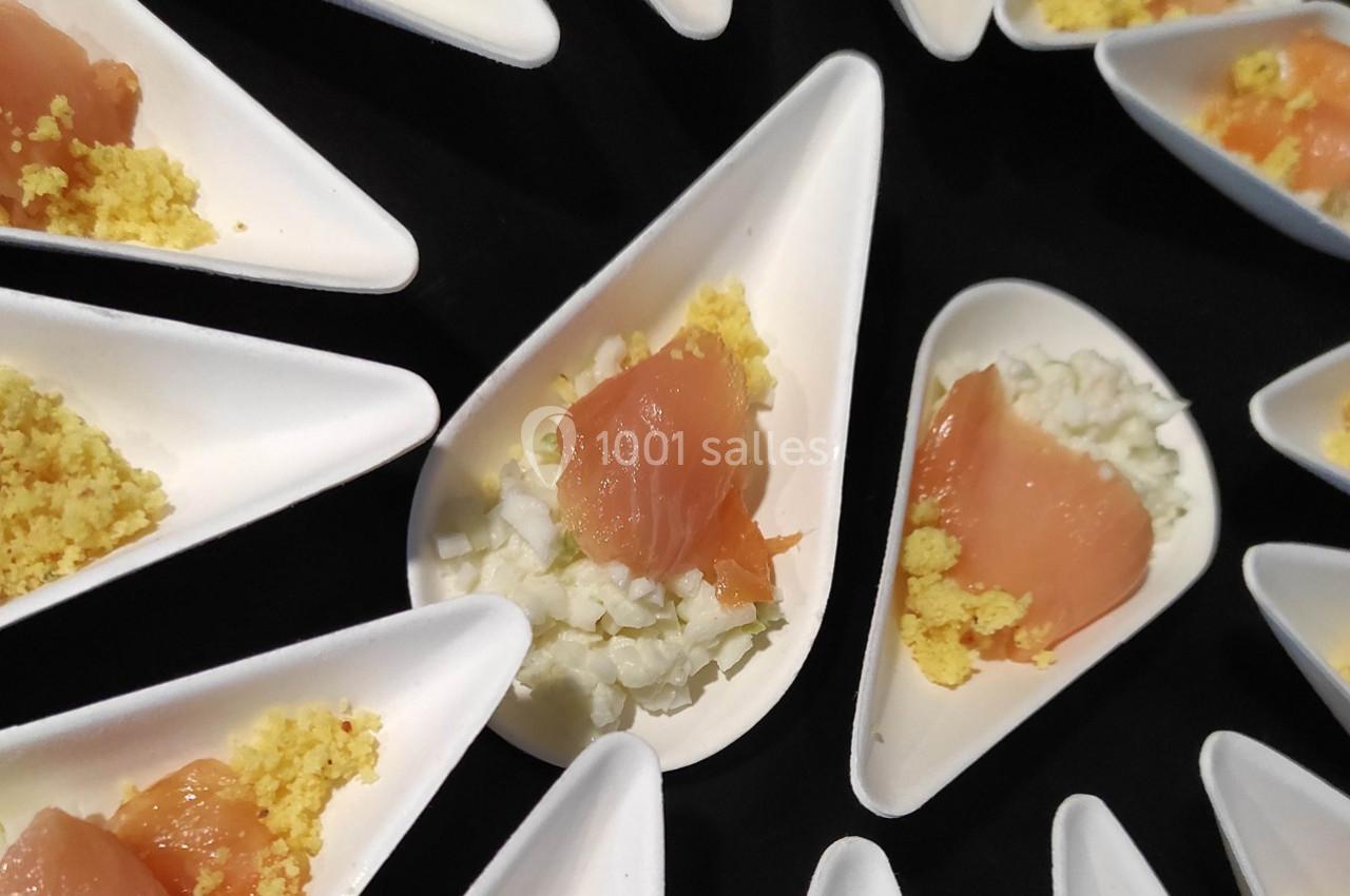 Portions individuelles de saumon fumé, œufs émiettés et oignons hachés présentées dans des cuillères blanches.