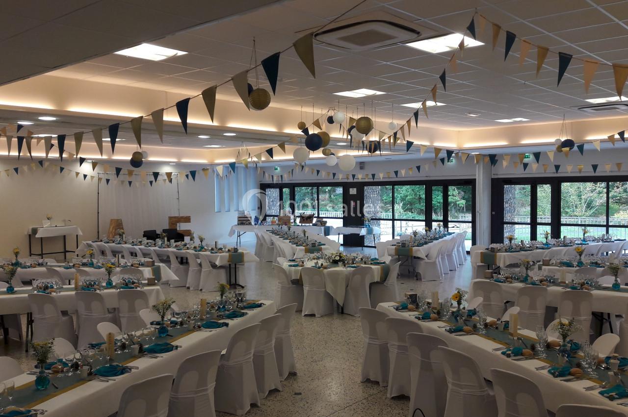 Salle de réception décorée avec des guirlandes et des tables dressées pour un événement festif.