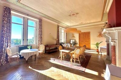 Terrasse ensoleillée avec tables dressées pour un buffet, entourée de végétation et d'arbres imposants.