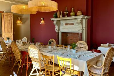 Terrasse ensoleillée avec tables dressées pour un buffet, entourée de végétation et d'arbres imposants.