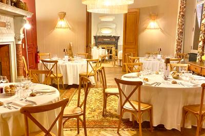 Terrasse ensoleillée avec tables dressées pour un buffet, entourée de végétation et d'arbres imposants.