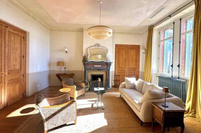 Paysage avec des champs verdoyants, des arbres, un lac en arrière-plan et des collines sous un ciel bleu dégagé.