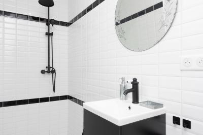 Salle de bain avec un grand miroir doré, deux vasques noires, robinetterie dorée et décoration moderne.