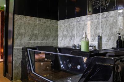 Salle de bain avec un grand miroir doré, deux vasques noires, robinetterie dorée et décoration moderne.