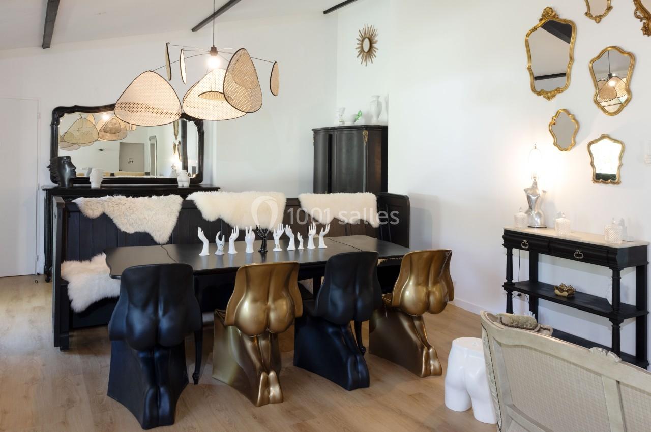 Salle à manger design avec chaises sculpturales, table noire, miroirs dorés et luminaires modernes dans un intérieur…