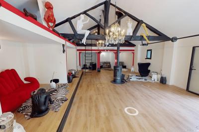 Extérieur d'une maison avec façade sombre, mobilier en osier et peaux, entourée de verdure et de bambous.