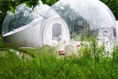 Extérieur d'une maison avec façade sombre, mobilier en osier et peaux, entourée de verdure et de bambous.