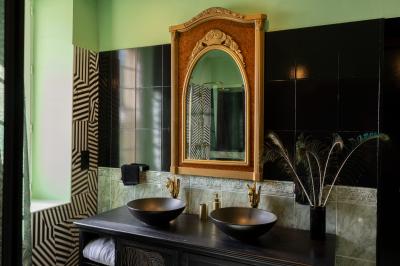 Extérieur d'une maison avec façade sombre, mobilier en osier et peaux, entourée de verdure et de bambous.