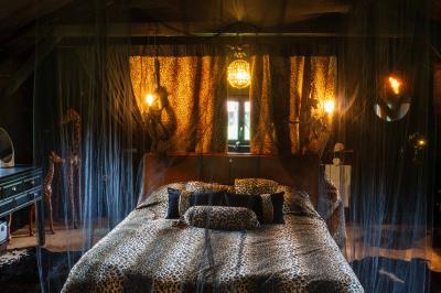 Extérieur d'une maison avec façade sombre, mobilier en osier et peaux, entourée de verdure et de bambous.