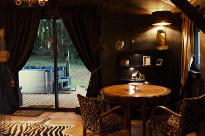 Extérieur d'une maison avec façade sombre, mobilier en osier et peaux, entourée de verdure et de bambous.