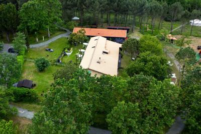 Extérieur d'une maison avec façade sombre, mobilier en osier et peaux, entourée de verdure et de bambous.