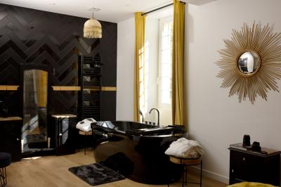 Extérieur d'une maison avec façade sombre, mobilier en osier et peaux, entourée de verdure et de bambous.