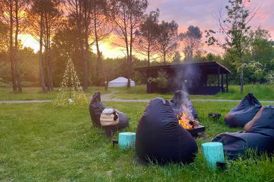 Extérieur d'une maison avec façade sombre, mobilier en osier et peaux, entourée de verdure et de bambous.