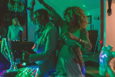 Extérieur d'une maison avec façade sombre, mobilier en osier et peaux, entourée de verdure et de bambous.