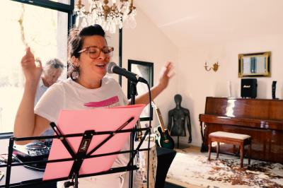 Extérieur d'une maison avec façade sombre, mobilier en osier et peaux, entourée de verdure et de bambous.