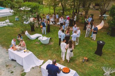 Extérieur d'une maison avec façade sombre, mobilier en osier et peaux, entourée de verdure et de bambous.