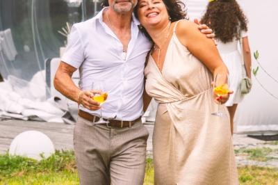 Extérieur d'une maison avec façade sombre, mobilier en osier et peaux, entourée de verdure et de bambous.