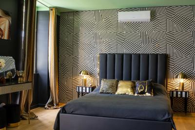 Extérieur d'une maison avec façade sombre, mobilier en osier et peaux, entourée de verdure et de bambous.