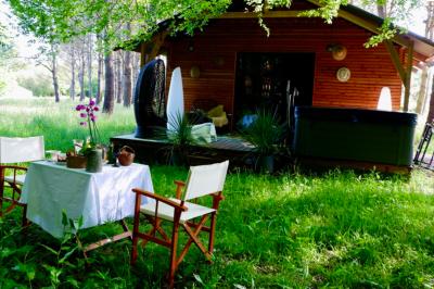 Extérieur d'une maison avec façade sombre, mobilier en osier et peaux, entourée de verdure et de bambous.