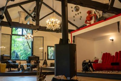 Extérieur d'une maison avec façade sombre, mobilier en osier et peaux, entourée de verdure et de bambous.