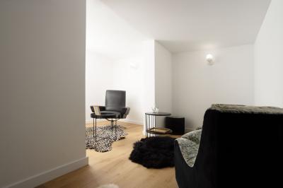 Extérieur d'une maison avec façade sombre, mobilier en osier et peaux, entourée de verdure et de bambous.