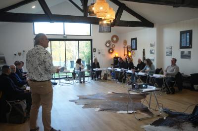Extérieur d'une maison avec façade sombre, mobilier en osier et peaux, entourée de verdure et de bambous.