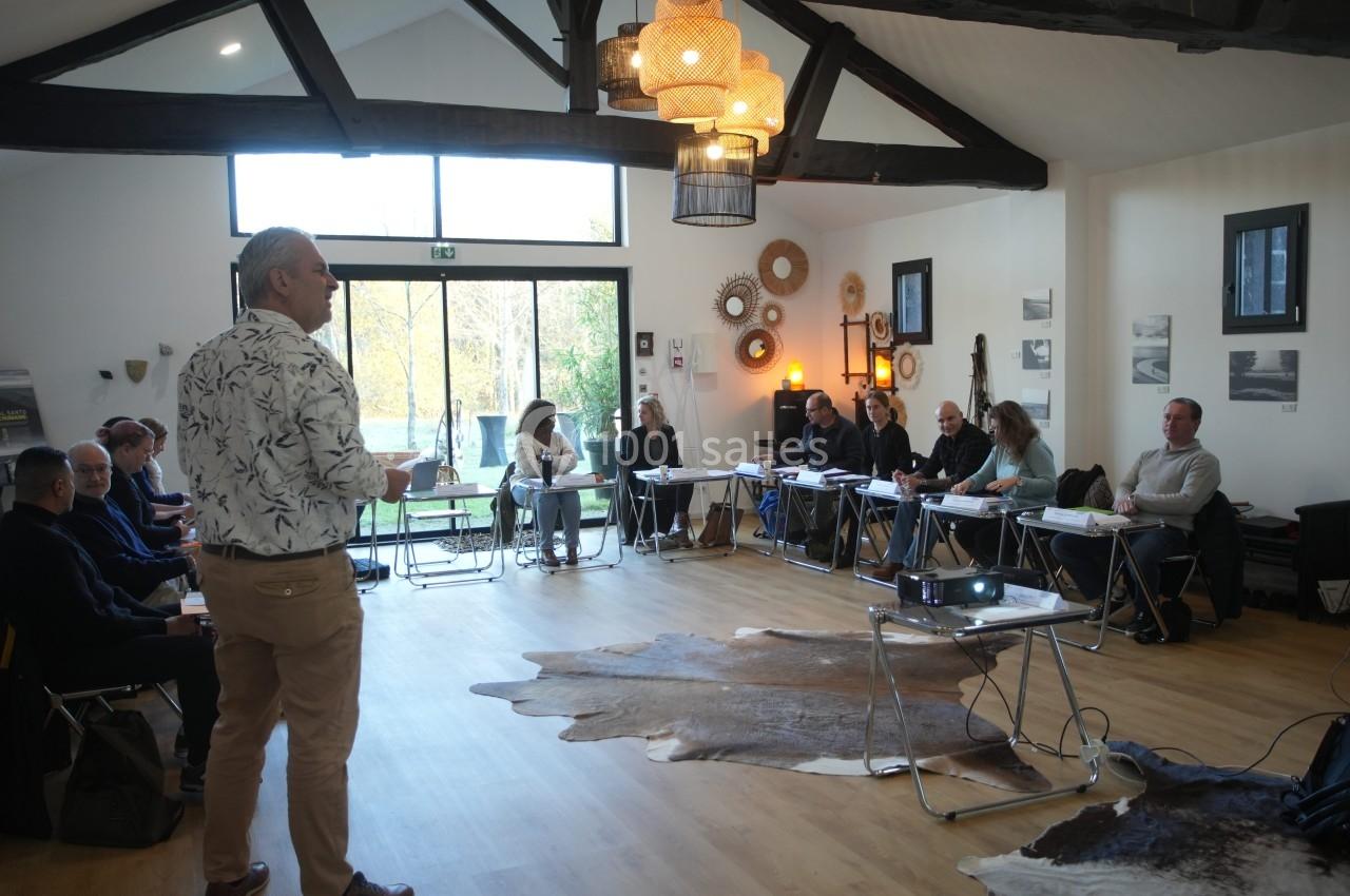 Un formateur s'adresse à un groupe de personnes assises dans une salle lumineuse avec des décorations murales.