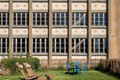 Espace lumineux avec plafond en bois, grandes fenêtres, mobilier varié et ambiance de loft industriel.