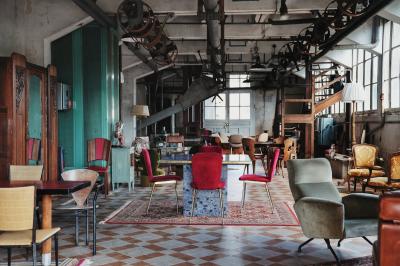 Espace lumineux avec plafond en bois, grandes fenêtres, mobilier varié et ambiance de loft industriel.