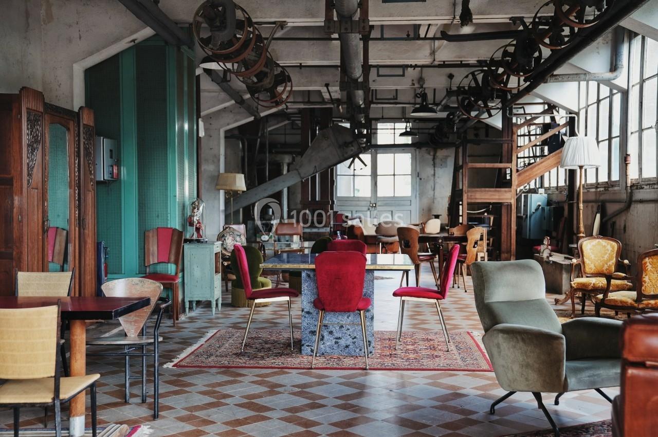 Salle aménagée dans un style vintage avec des meubles éclectiques, des chaises colorées et un sol en carreaux.