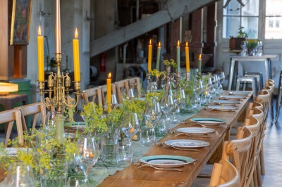 Espace lumineux avec plafond en bois, grandes fenêtres, mobilier varié et ambiance de loft industriel.