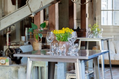 Espace lumineux avec plafond en bois, grandes fenêtres, mobilier varié et ambiance de loft industriel.