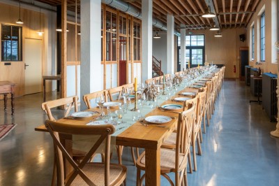 Table en bois dressée pour un repas, avec assiettes, verres, couverts, bougies et décoration centrale élégante.