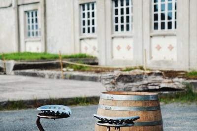 Espace lumineux avec mobilier en bois et cuir, grandes fenêtres, plafond en poutres apparentes et sol en béton.