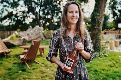 Espace lumineux avec mobilier en bois et cuir, grandes fenêtres, plafond en poutres apparentes et sol en béton.