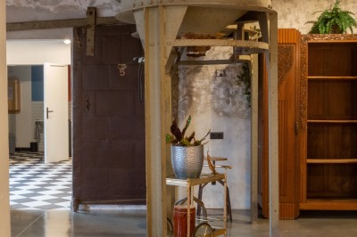 Étagère métallique décorative avec quelques bouteilles, un plateau et des plantes, éclairée par deux lampes murales.