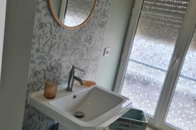 Douche à l'italienne avec carrelage sombre à gauche et lavabo blanc sur meuble en bois à droite.